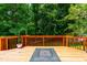 Spacious wood deck featuring an orange railing, a black fire pit, and peaceful views of the wooded area at 8116 Owenston Ct, Raleigh, NC 27612