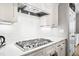 White kitchen showcasing a gas range with stainless steel hood, marble countertops, and subway tile backsplash at 9713 San Remo Pl, Wake Forest, NC 27587