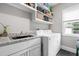 Convenient laundry room equipped with washer, dryer, storage shelves, sink, and granite countertops at 9713 San Remo Pl, Wake Forest, NC 27587