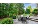 Serene backyard with a stone patio, outdoor seating, and mature trees at 101 Synandra Ln, Holly Springs, NC 27540