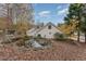 Picturesque backyard featuring a tranquil pond surrounded by mature trees and colorful autumn leaves at 103 Pony Express Cv, Louisburg, NC 27549