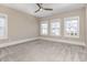An empty bedroom with neutral walls, carpeted flooring, and three large windows at 1131 Lowland St, Apex, NC 27523