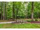 Outdoor patio featuring Adirondack chairs, beautiful landscaping, and a serene wooded backdrop at 1301 King Cross Ct, Raleigh, NC 27614
