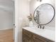 Bathroom with hardwood floors, vanity, white countertop, round mirror, and decorative flowers at 1301 King Cross Ct, Raleigh, NC 27614