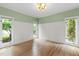 Sunlit room with hardwood floors, wainscoting, fresh green paint, and three large windows at 1301 King Cross Ct, Raleigh, NC 27614
