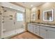 Modern bathroom featuring a glass-enclosed shower, double vanity with granite countertops, and illuminated mirrors at 14 Marigold Pl, Durham, NC 27705