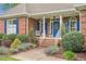 Charming brick home featuring a welcoming front porch, landscaped garden, and blue shutters at 14 Marigold Pl, Durham, NC 27705