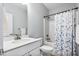 Clean bathroom with a white vanity, toilet, and shower/tub combination with a patterned blue and white curtain at 1727 Pinecliff Ct, Fuquay Varina, NC 27526