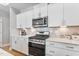 Well-equipped kitchen featuring white cabinets, stainless steel appliances, modern countertops, and tiled backsplash at 1727 Pinecliff Ct, Fuquay Varina, NC 27526