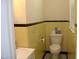 Bathroom with yellow wall tiles, a toilet and a sink, showcasing a clean design at 1809 S Garnett Ext, Henderson, NC 27536