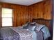 Bedroom with wood paneled walls features a bed with dark patterned bedding and a window at 1809 S Garnett Ext, Henderson, NC 27536