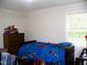 Bright bedroom with blue themed bedspread and wooden dresser for ample storage at 1809 S Garnett Ext, Henderson, NC 27536