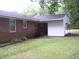 Brick home featuring a carport, small patio area, and a green lawn surrounded by mature trees at 1809 S Garnett Ext, Henderson, NC 27536