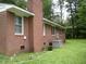 Brick home with a brick chimney, trimmed bushes, and central air conditioning unit at 1809 S Garnett Ext, Henderson, NC 27536