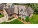 Aerial view of brick home showcasing lush landscaping, well-manicured lawn, and a two-car attached garage at 2014 Muirfield Ct, Elon, NC 27244
