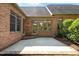 A brick home's outdoor patio is accessible via a doorway and large windows, offering a serene retreat at 2014 Muirfield Ct, Elon, NC 27244