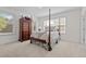 Bright bedroom featuring neutral carpet, multiple windows, and an antique chest and four-poster bed at 2014 Muirfield Ct, Elon, NC 27244