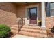 Inviting front entrance with brick steps, a decorative railing, and a classic maroon door at 2014 Muirfield Ct, Elon, NC 27244