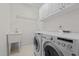 Functional laundry room with white cabinetry, sink, and modern washer and dryer at 2014 Muirfield Ct, Elon, NC 27244