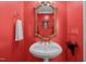 Stylish powder room featuring a pedestal sink, decorative mirror, and red accent wall at 2014 Muirfield Ct, Elon, NC 27244