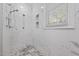 Modern bathroom shower featuring a marble tile surround, mosaic floor, and window with natural light at 2014 Muirfield Ct, Elon, NC 27244