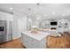 Open-concept kitchen with a center island, pendant lights, stainless steel fridge, and view of the living room at 2083 Amalfi Pl, Apex, NC 27502