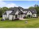 Spacious two-story home with white brick, dark trim, a manicured lawn, and mature trees creating privacy at 2220 Inwood Landing Ct, Raleigh, NC 27603