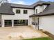 Three-car garage with glass doors, a large parking pad, and well-manicured landscaping and trees at 2220 Inwood Landing Ct, Raleigh, NC 27603