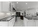 Modern kitchen featuring marble floors, black countertops, high-end appliances, and sleek, white custom cabinetry at 2220 Inwood Landing Ct, Raleigh, NC 27603
