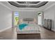 Luxury main bedroom featuring a tray ceiling with a chandelier, hardwood floors, and backyard views at 2220 Inwood Landing Ct, Raleigh, NC 27603