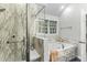 Relaxing bathroom featuring a soaking tub, shower, and marble-style wall paneling with natural light at 2325 Old Oak Pl, Hillsborough, NC 27278