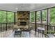 Relaxing screened porch with a stone fireplace, comfortable seating, and views of the serene wooded surroundings at 2325 Old Oak Pl, Hillsborough, NC 27278