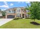 Beautiful two story home with a well manicured lawn, stone and brick exterior, and gray two car garage at 2333 Lantern Walk Ln, Wake Forest, NC 27587