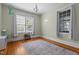 Bright bedroom with hardwood floors, chandelier, and two windows with blinds and curtains at 311 N Gregson St, Durham, NC 27701
