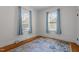 Bedroom featuring two windows with blinds, light blue curtains, and hardwood floors with rug at 311 N Gregson St, Durham, NC 27701