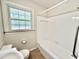 Standard bathroom with white tiled shower-tub, white toilet, and a window with a patterned glass at 322 S Dixon Ave, Cary, NC 27511