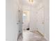 A bright hallway with marble tile flooring leads to a wallpapered bathroom and features white doors with gold hardware at 3405 E Jameson Rd, Raleigh, NC 27604