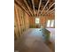 An unfinished living room shows exposed beams, a window, wiring, and a door frame leading to the outside at 432 Golden Dragonfly St, Wake Forest, NC 27587