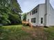View of the home's rear exterior and backyard with a new wood deck, surrounded by mature trees at 4903 Bridgewood Dr, Durham, NC 27713