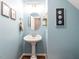 Charming powder room features pedestal sink, an oval mirror, and coastal-themed wall art at 5009 Beckwyck Dr, Fuquay Varina, NC 27526