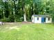 Charming outbuilding with blue trim and windows in a shady, grassy area surrounded by trees at 518 Heater Dr, Cary, NC 27511