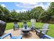 Backyard featuring Adirondack chairs around a fire pit on a stone patio with a grassy area and mature trees at 5516 Colonial Oaks Dr, Apex, NC 27539