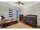 Cozy bedroom with hardwood floors, ceiling fan, and a large window covered with blue and white striped curtains at 5516 Colonial Oaks Dr, Apex, NC 27539