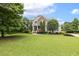 Charming two-story home with stone accents, mature trees, and a sprawling green lawn at 5516 Colonial Oaks Dr, Apex, NC 27539