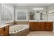 Elegant main bathroom featuring a jacuzzi tub with tile surround and bright lighting at 5516 Colonial Oaks Dr, Apex, NC 27539