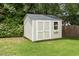 Backyard shed for additional storage with double doors, a window box, and surrounded by green grass and trees at 5516 Colonial Oaks Dr, Apex, NC 27539
