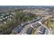 The aerial shot shows a neighborhood, a school, and a forest, set against a backdrop of a clear, blue sky at 629 Newlyn Dr, Raleigh, NC 27606