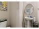 Stylish half bathroom with pedestal sink, round mirror, and neutral color scheme at 629 Newlyn Dr, Raleigh, NC 27606