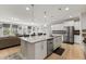 Modern kitchen featuring stainless steel appliances, white cabinets, and an island with stone countertop open to living room at 629 Newlyn Dr, Raleigh, NC 27606