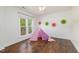 Cozy bedroom with hardwood floors, window views, a cute teepee tent, and playful decorations at 8913 Walking Stick Trl, Raleigh, NC 27615